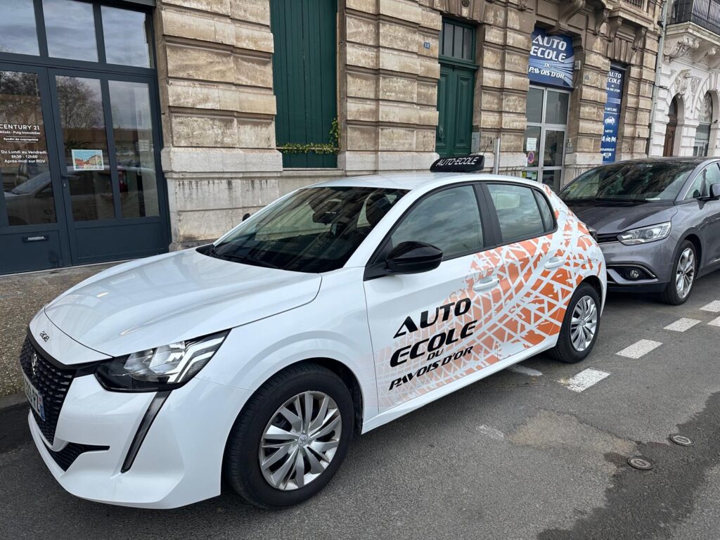 Véhicule orange de l’Auto-école du Pavois d’Or servant à la formation au permis B, stationné devant l'auto-école