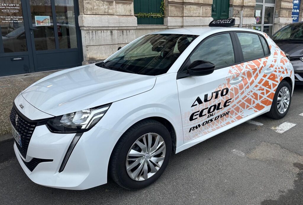 Véhicule orange de l’Auto-école du Pavois d’Or servant à la formation au permis B, stationné devant l'auto-école